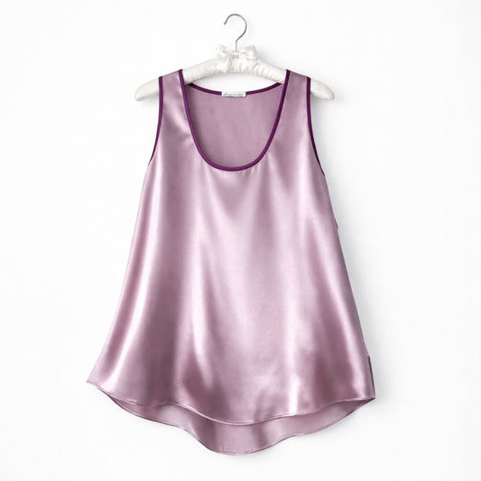 Pink silk satin camisole top hanging on a white hanger against a white background