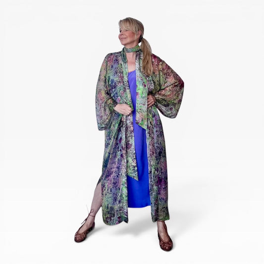 Model wearing a long printed silk chiffon kimono and matching scarf over a blue dress on a white background