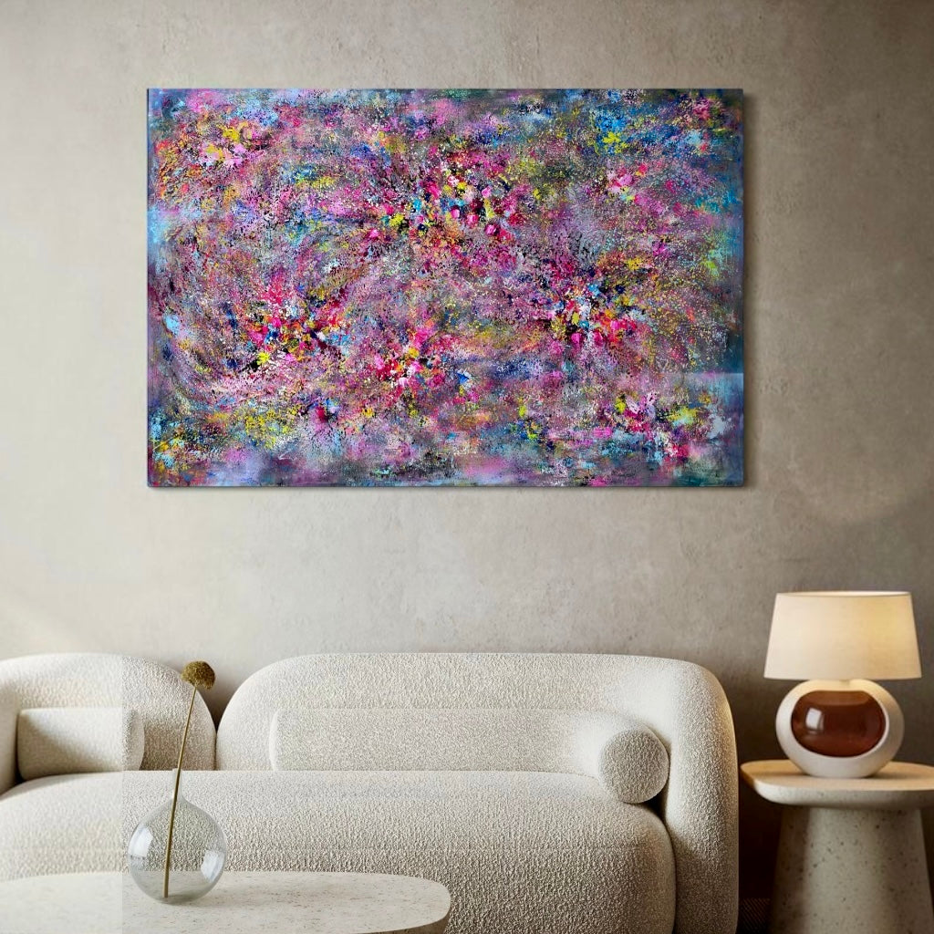 A colorful abstract canvas wall art print featuring pink, purple, blue, and gold brushstrokes, displayed in a modern living room setting above a textured cream sofa.