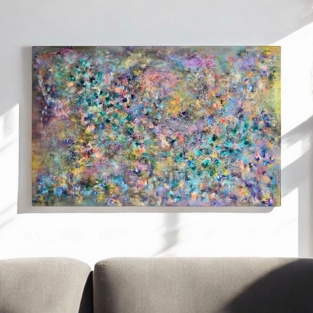 A large rectangular abstract canvas painting with a dense, textured floral-like pattern in pastel blue, purple, green, yellow, and pink tones, displayed on a white wall above a gray sofa.