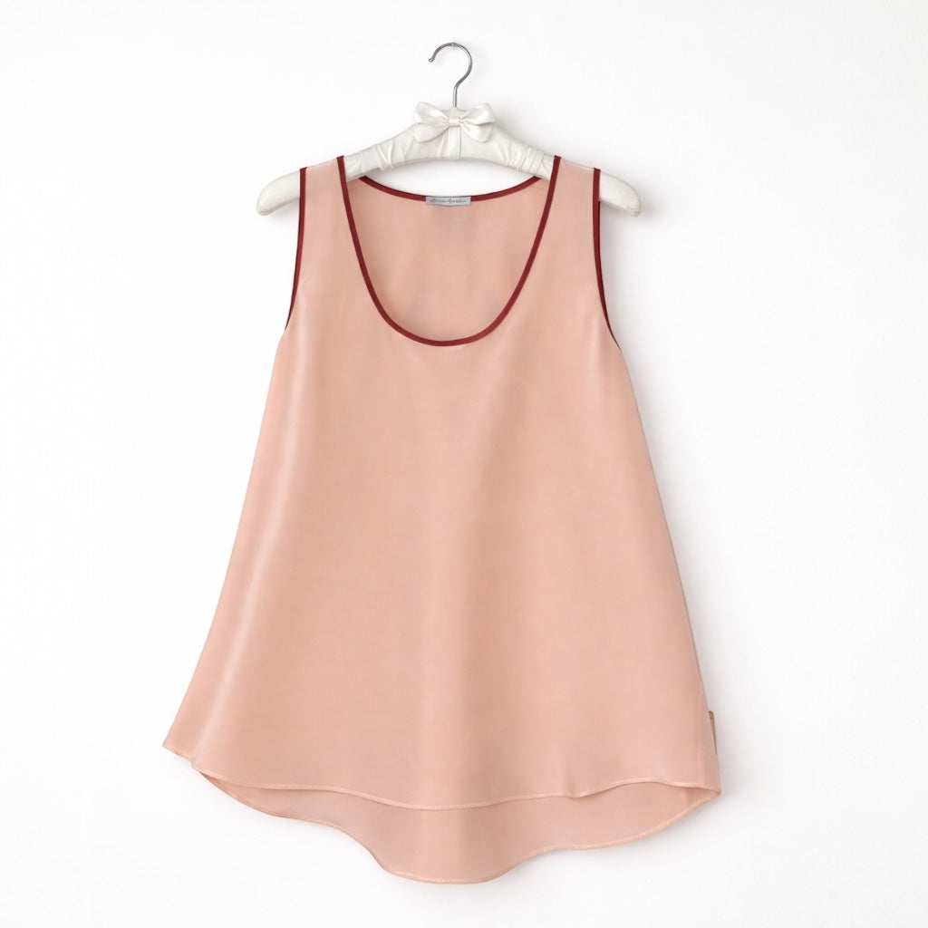 Pink sleeveless top with red trim on a hanger against a white background
