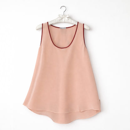 Pink sleeveless top with red trim on a hanger against a white background
