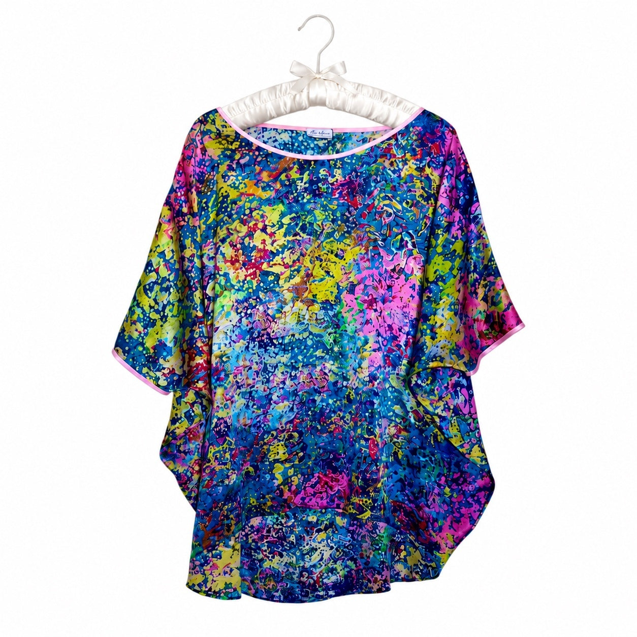 Colorful abstract patterned shirt on a white hanger against a white background