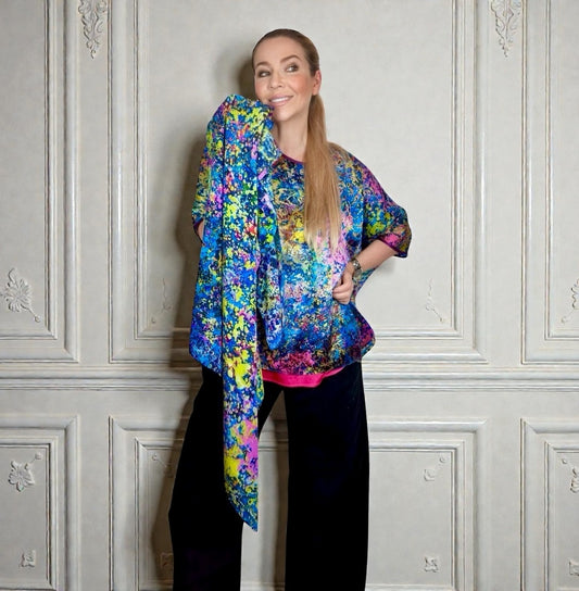 Woman wearing a colorful floral jacket against a gray wall.