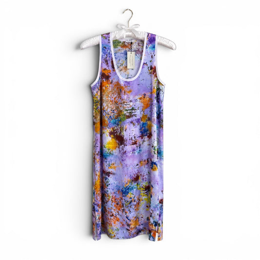 A sleeveless tank dress with a purple and lavender abstract paint-splatter pattern, hanging on a white plastic hanger against a plain white background.