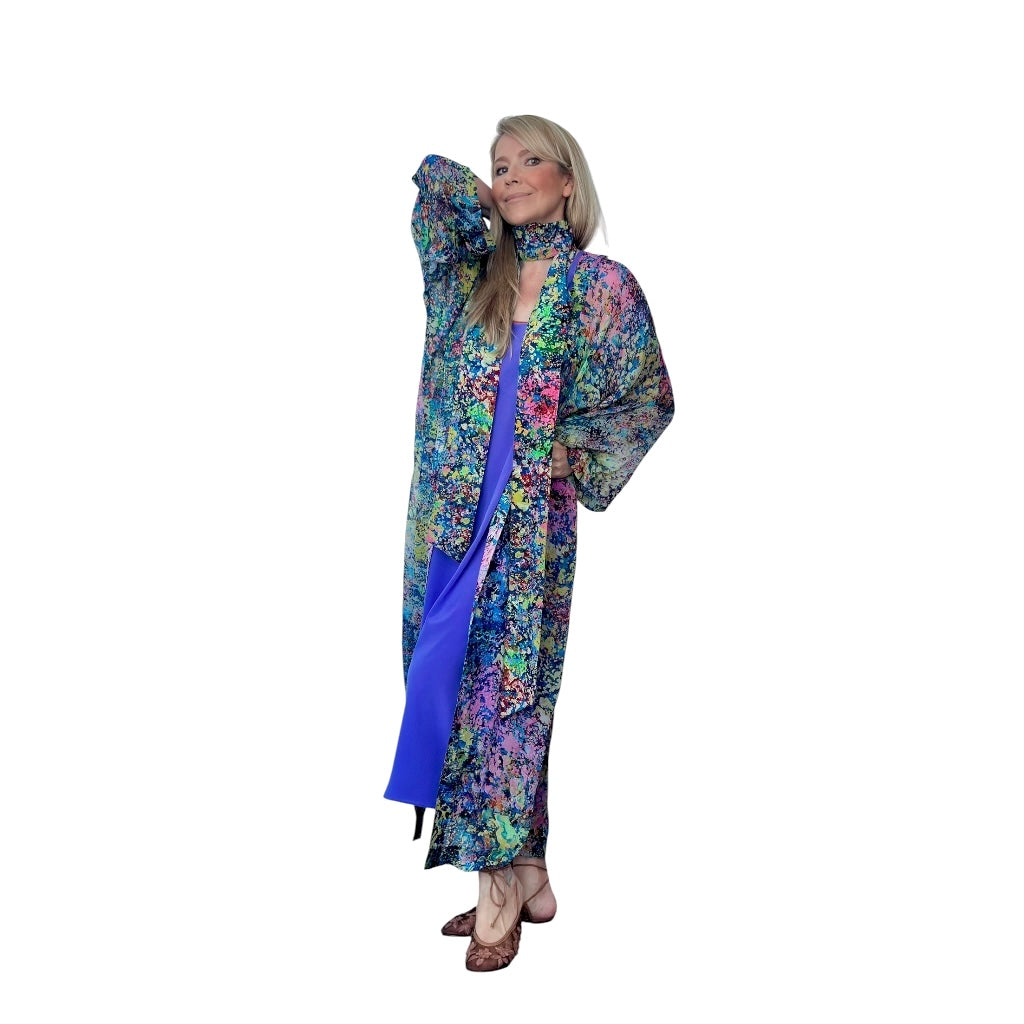 Woman wearing a colorful floral coat with a blue scarf on a white background