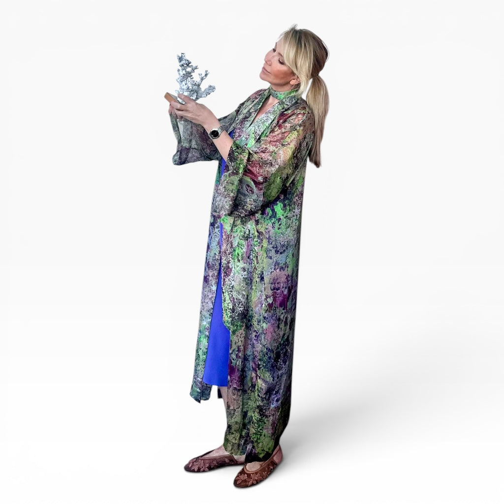 Woman wearing a colorful floral dress holding a plant against a white background