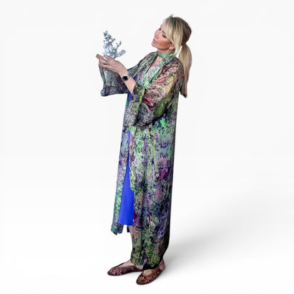 Woman wearing a colorful floral dress holding a plant against a white background