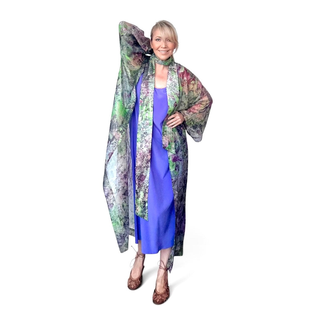 Woman wearing a long, patterned coat over a blue dress on a white background
