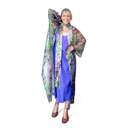 Woman wearing a long, patterned coat over a blue dress on a white background