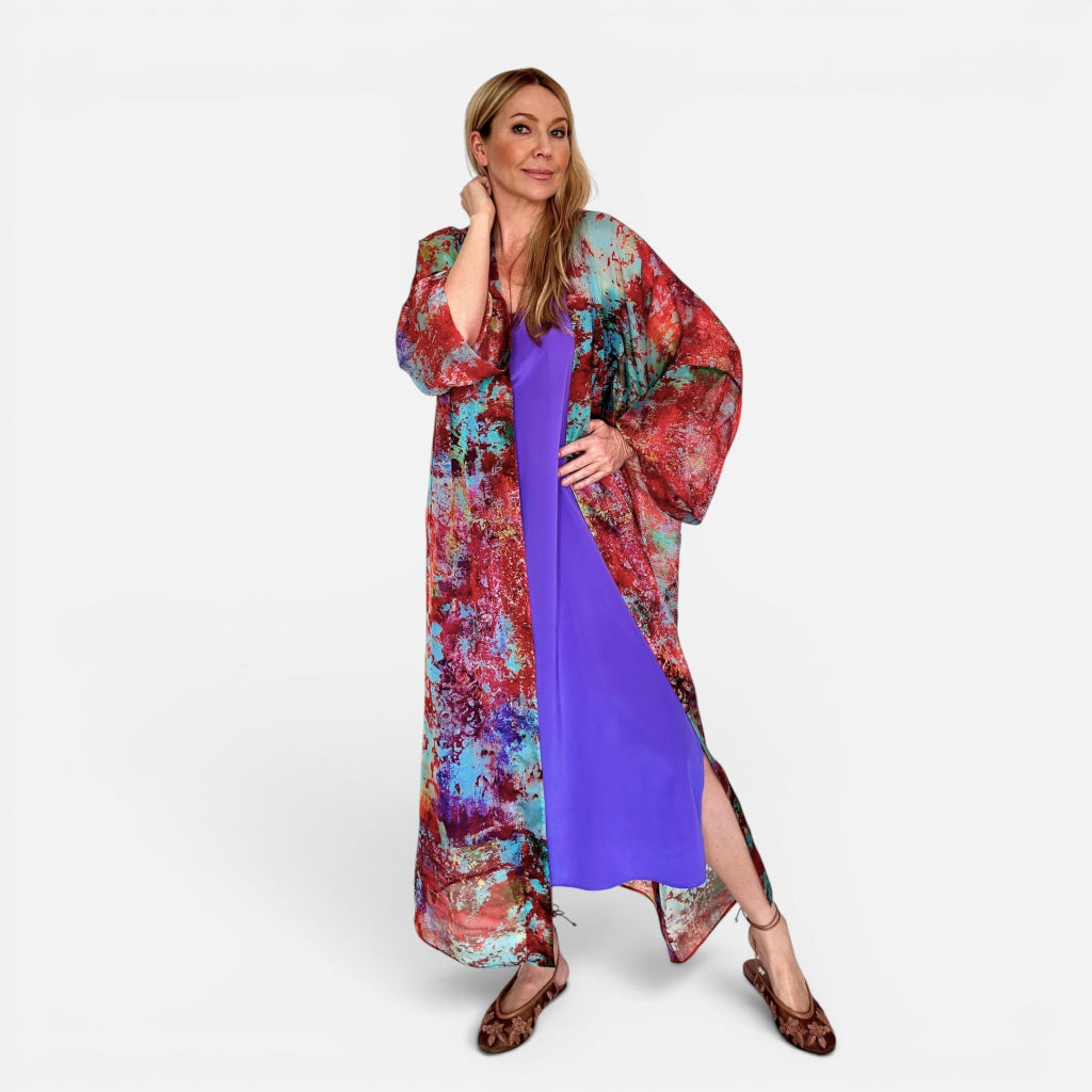 Woman wearing a colorful kimono-style garment over a purple dress on a white background