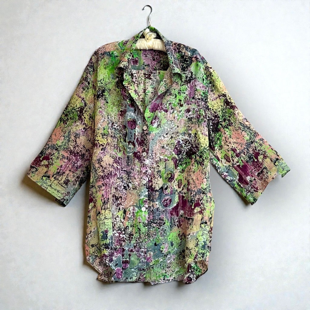 green shirt handing on hanger against a white wall