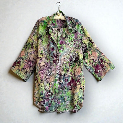green shirt handing on hanger against a white wall
