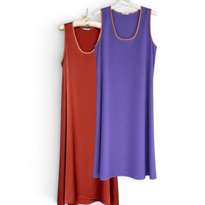 Two sleeveless dresses, one red and one purple, hanging on a white background.