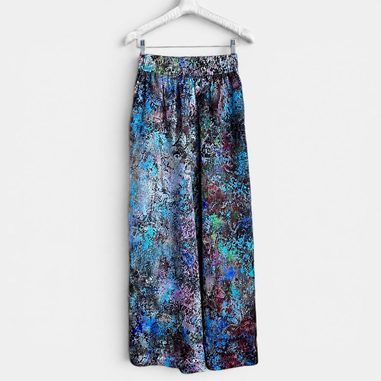 Colorful floral-patterned pants on a hanger against a white background