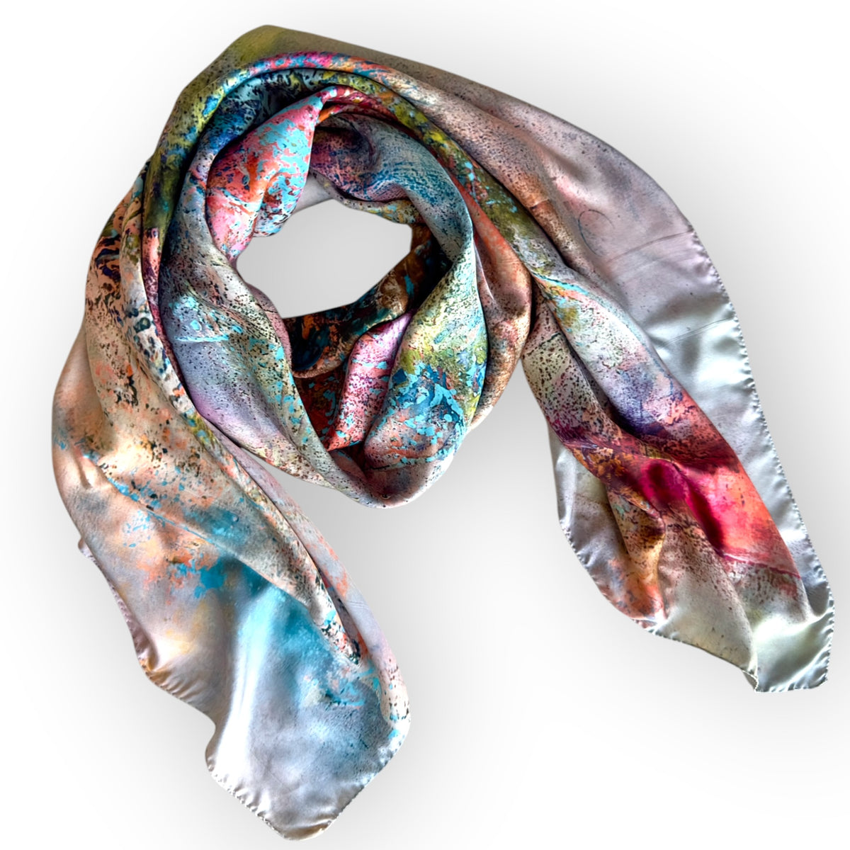 A square silk scarf with a metallic, iridescent finish, featuring a marbled pattern of silver, blue, pink, and gold hues, draped against a white background.