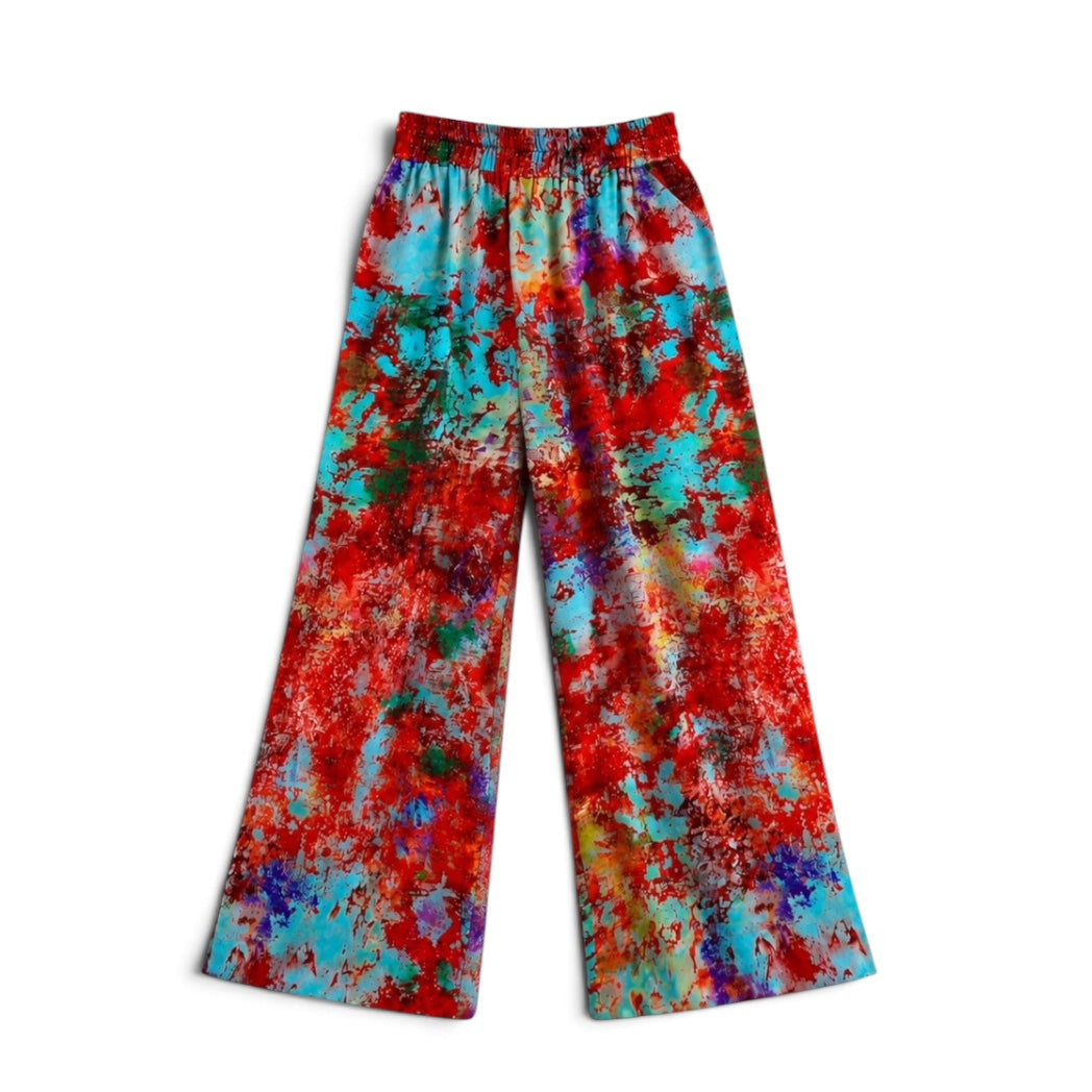 Wide-leg pants with an elastic waistband, featuring a vibrant multicolor abstract paint-splatter pattern in red, turquoise, blue, green, and purple on a white background.