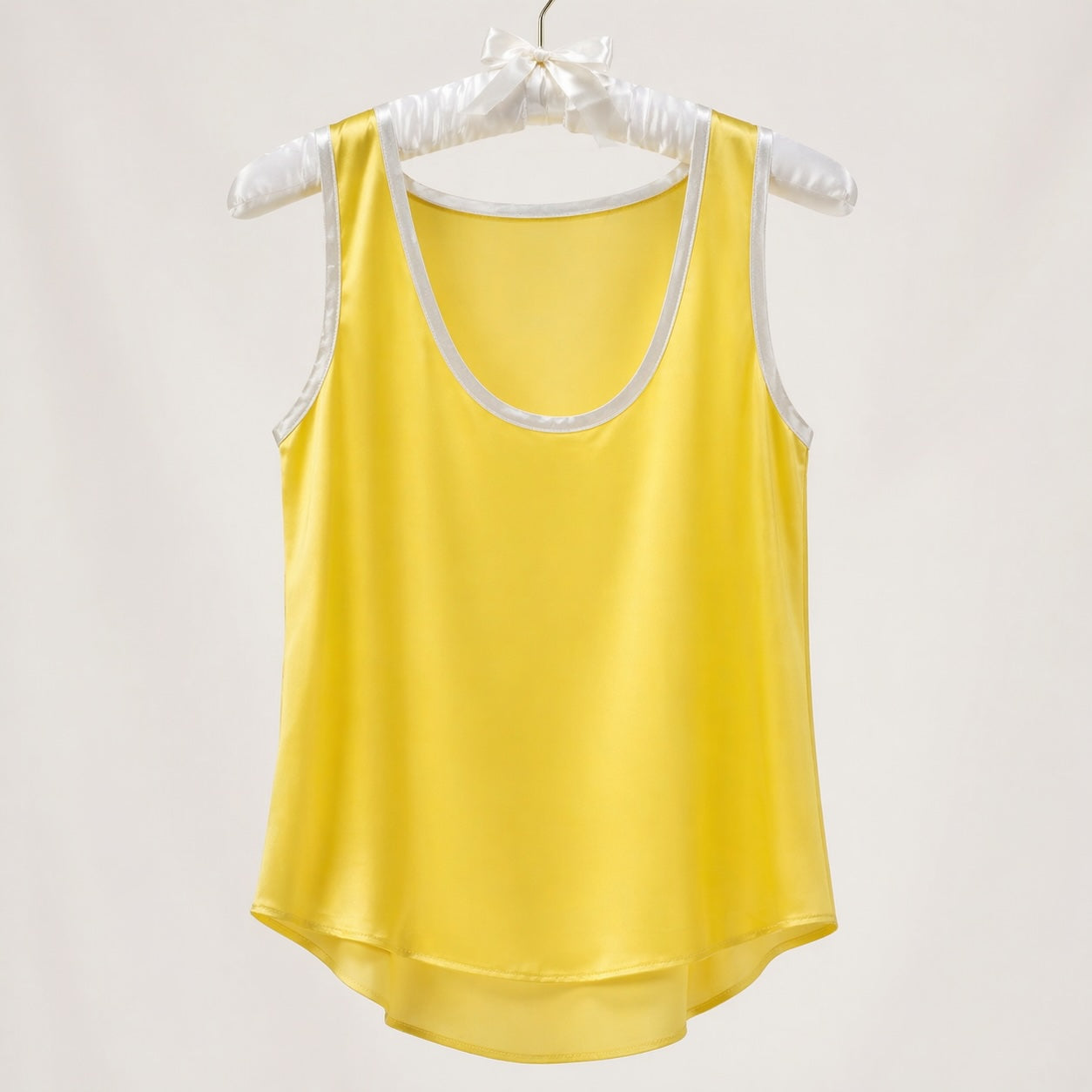 Yellow tank top with white trim on a hanger against a light gray background